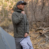 Man wearing insulated hooded down jacket zipping the front closure for warmth.