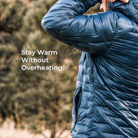 A close-up of a person wearing a dark blue quilted puffer jacket outdoors, with blurred trees in the background and the text 'Stay Warm Without Overheating' on the left.