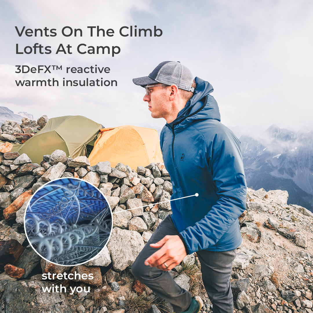 A man wearing a blue hooded jacket and gray cap stands on a rocky mountainside with tents and misty peaks in the background. Text reads 'Vents On The Climb Lofts At Camp' and '3DeFX™ reactive warmth insulation,' with a circular inset showing the jacket's textured fabric.