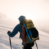 side view of mountaineer wearing blue technical hoodie and rope pack