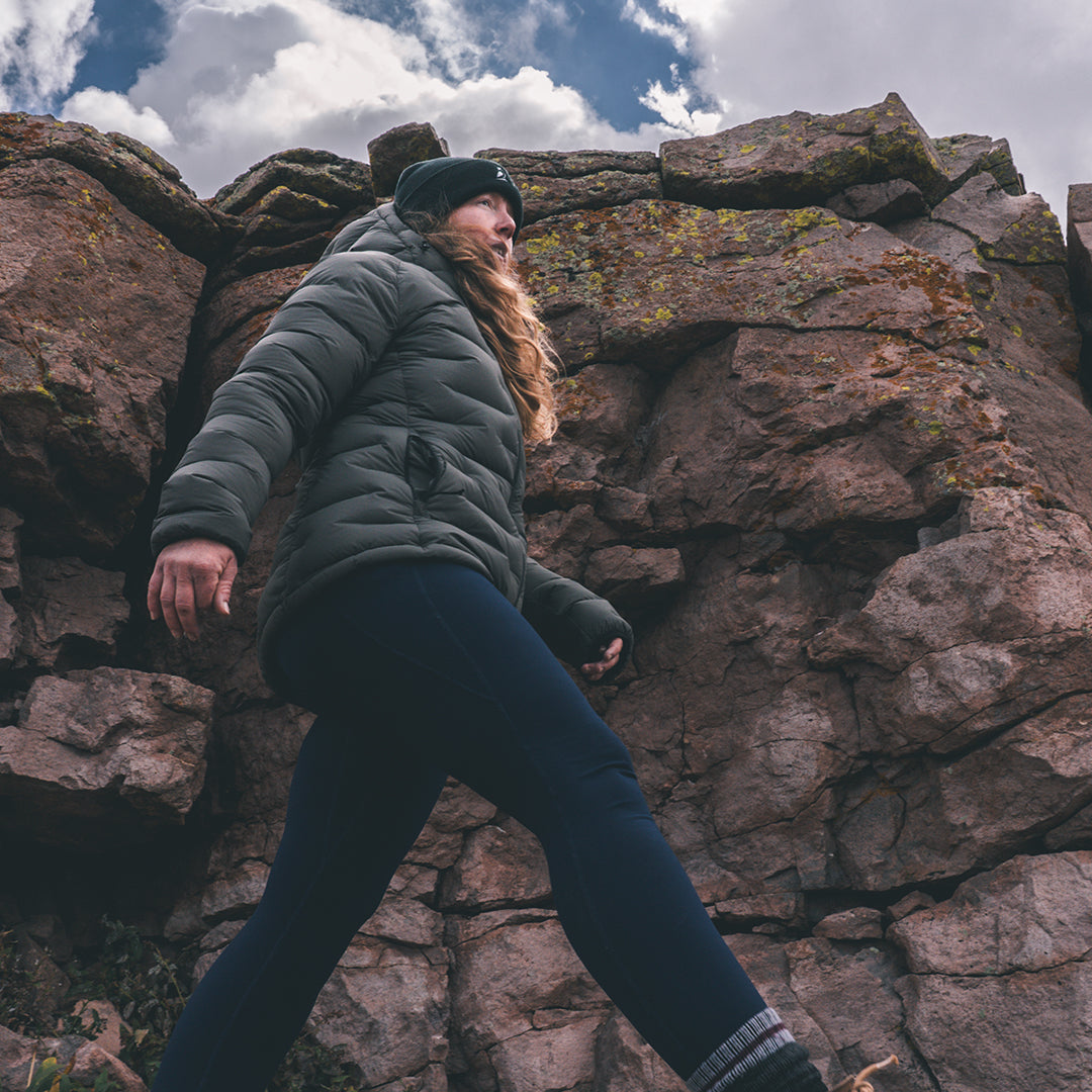 woman wearing dark gray puffy down jacket in high mountain environment.