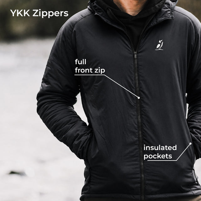 A man wearing a black YKK zippers lightweight jacket, with white text callouts pointing to the 'full front zip' and 'insulated pockets' on a blurred outdoor background.
