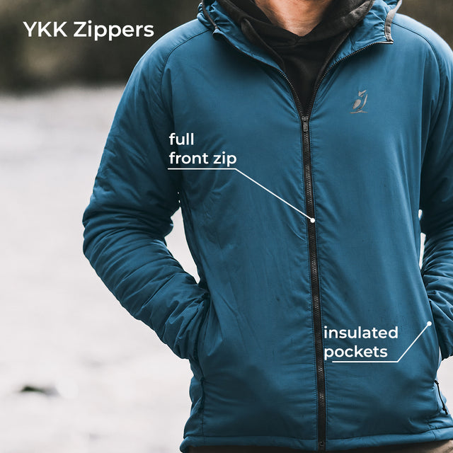 A person wearing an insulated jacket with a full front zipper and zippered pockets, shown outdoors with white text callouts reading 'YKK Zippers', 'full front zip', and 'insulated pockets'.