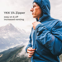 A man wearing a blue hooded rain jacket stands outdoors in front of mountains, with text on the left reading 'YKK 1/4 Zipper easy on & off increased venting.' Because a person and real outdoor environment are present, this is Lifestyle rather than Product/Packaging.