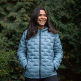 Woman wearing insulated hooded down jacket shown from the front outdoors.