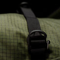 Close-up of a green textured bag with a black strap and buckle.