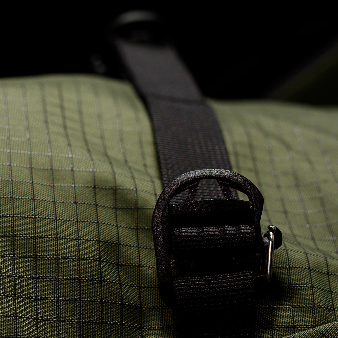 Close-up of a green textured bag with a black strap and buckle.