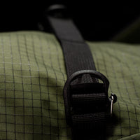 Close-up of a green textured bag with a black strap and buckle.