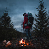 Camper standing by a fire with the Shadowlight Ultralight Backpack